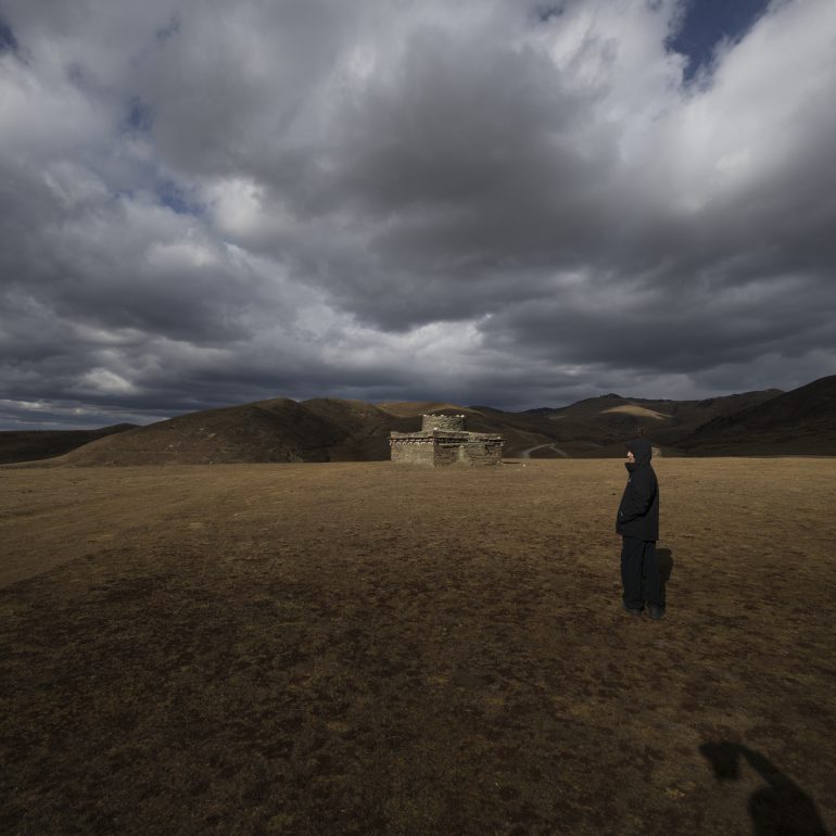 Explore the wild, open grasslands behind Muya Great Monastery under a dramatic sky.