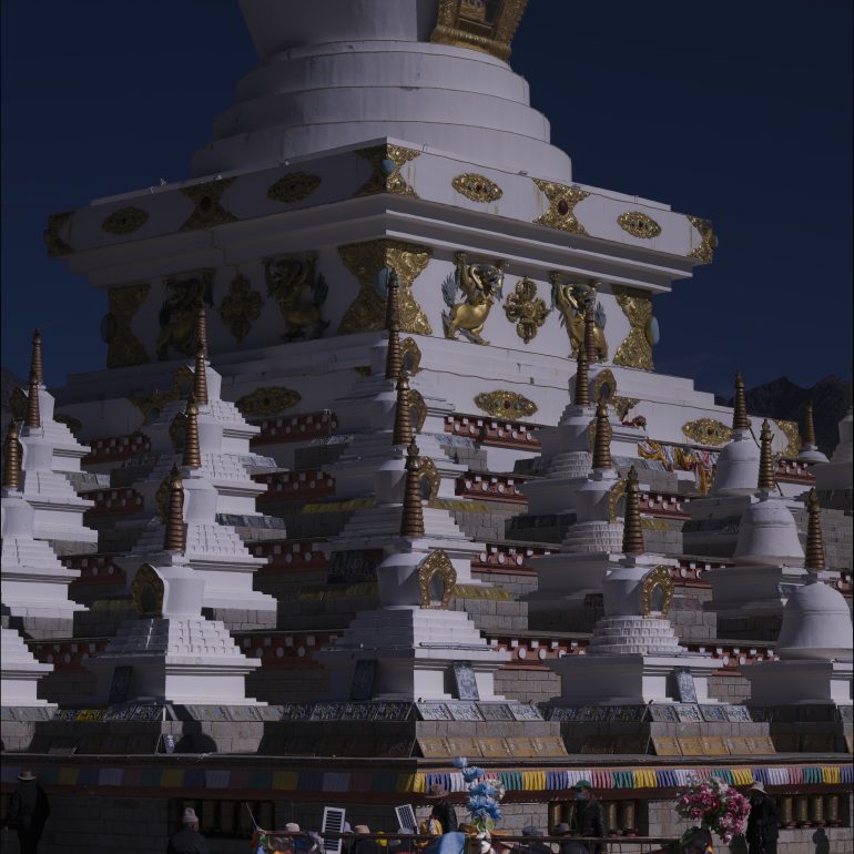 Sunlight bathes LiTang Stupa; pilgrims rest after circumambulation, prayer flags fluttering, time standing still in beauty.